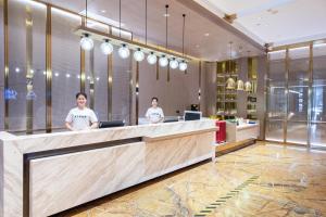 a lobby with two men standing at a reception desk at Atour X Hotel Haikou International Trade Center in Haikou