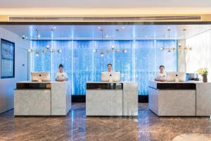 a lobby with three men working on laptops at Atour Light Hotel Zhuhai Lovers Road Grand Theater in Zhuhai