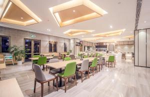 un restaurant avec des chaises et des tables vertes dans une cafétéria dans l'établissement Atour Hotel Shengtai West Road South Railway Station Nanjing, à Nankin