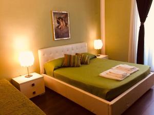 ローマにあるB&B アレクサンダーのベッドルーム1室(緑のシーツとランプ2つ付)