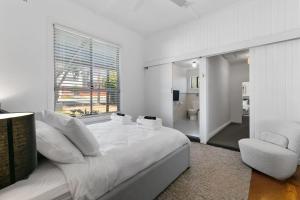 um quarto branco com uma cama grande e uma cadeira em Christies Garden - A Beachside Entertainer's Gem em Port Noarlunga
