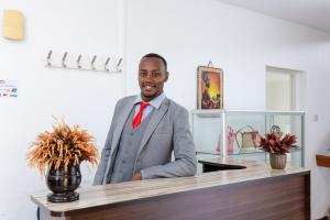 a man in a suit and tie standing at a counter at Bonsai Village in Nairobi
