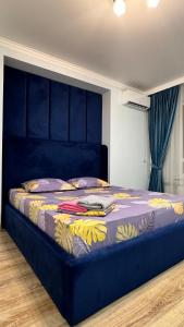 een slaapkamer met een blauw bed met een blauw hoofdeinde bij ЖК Lake town 3 in Alma-Ata
