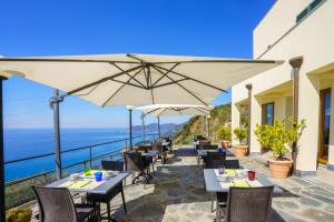 a restaurant with tables and umbrellas overlooking the ocean at Albergo Luna di Marzo in Volastra