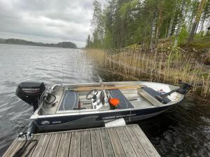 a small boat parked at a dock on a lake at Tarula Holiday Home in Melkoniemi