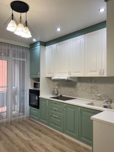 a kitchen with green and white cabinets and wooden floors at ЖК Lake town 3 in Almaty