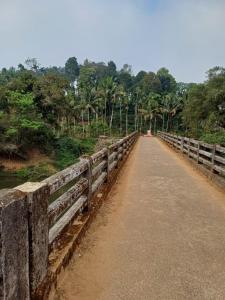 een brug over een weg met bomen op de achtergrond bij River Valley in Mananthavady