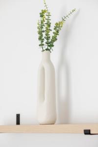 a white vase with flowers in it sitting on a shelf at Modern Studios in the Centre of Poznań by Noclegi Renters in Poznań +23 photos