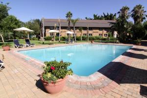 - une grande piscine avec des plantes en pot à côté d'un bâtiment dans l'établissement Cresta Lodge Gaborone, à Gaborone