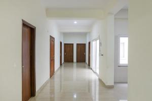 un couloir vide avec des murs blancs et des portes en bois dans l'établissement FabHotel Grihum, à Indirapuram