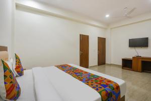 - une chambre avec un lit et une télévision à écran plat dans l'établissement FabHotel Grihum, à Indirapuram
