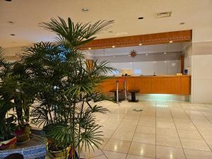 a lobby with a waiting room with palm trees at Motosu Phoenix Hotel in Fujikawaguchiko