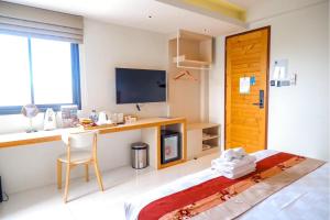 um quarto de hotel com uma secretária, uma cama e uma televisão em LA PINO HOTEL em Songkhla