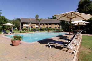 a pool with two lawn chairs and an umbrella at Cresta Lodge Gaborone in Gaborone
