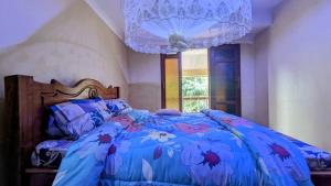 a bed with a blue comforter and a chandelier at MICHELLE HOME STAY in Hambayo