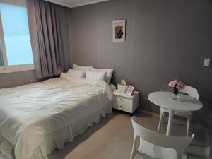a bedroom with a bed and a table and a window at Stay Mido in Busan