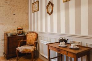 Le Manoir des Marronniers في Sully: كرسي وطاولة في غرفة مع كرسي ومرآة