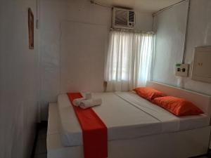 Cama en habitación pequeña con ventana en Orange Mangrove Pension House, en Puerto Princesa City