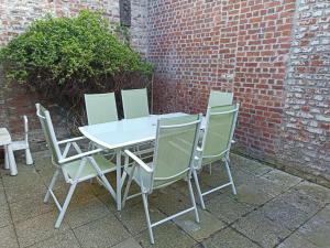 une table et des chaises blanches à côté d'un mur de briques dans l'établissement Place du Canada 2, à Valenciennes