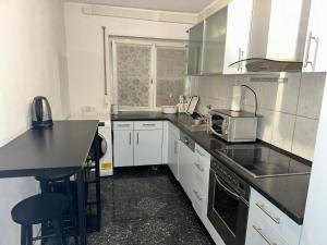 uma cozinha com armários brancos e um balcão preto em TULUM APARTMENTS - STUTTGART CITY em Stuttgart