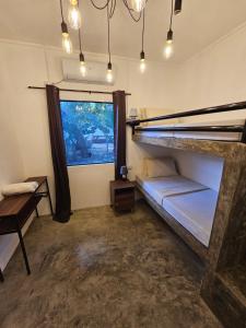 Habitación con cama, escritorio y ventana. en Crazy Bears Hostel, en Moalboal