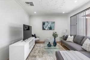 a living room with a couch and a tv at Coastal Charm: Halls Head Getaway in Mandurah in Mandurah