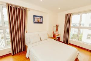a bedroom with a white bed and large windows at Căn hộ 3 phòng ngủ cao cấp view biển in Ha Long