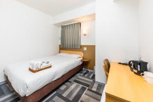 福岡市にあるホテルネクサス 博多山王のベッドとデスクが備わるホテルルームです。