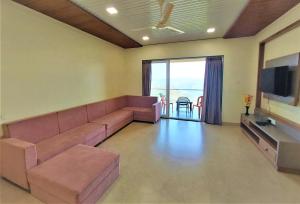 a living room with a couch and a flat screen tv at Vinayaka Holiday Homes - Infinity Pool and Breathtaking Valley View in Panchgani