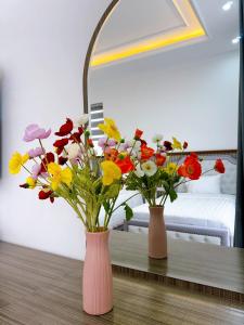 dos jarrones con flores en una mesa en una habitación en Phượng Hoàng villa en Ha Long
