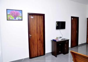 a room with a door and a desk and a television at Whiteway Homestay in Kūmudi