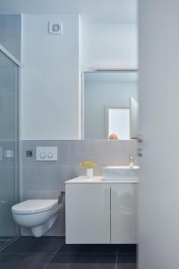 a white bathroom with a toilet and a sink at Villa Roca in Vis
