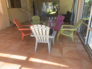 a group of colorful chairs and tables on a porch at Les Hibiscus in Saint-Philippe