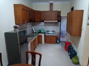 - une cuisine avec des placards en bois et un réfrigérateur noir dans l'établissement Ndalem Cemara Homestay, à Yogyakarta