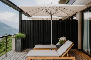 une terrasse avec une chaise et un parasol dans l'établissement farnhaus, à Tirolo