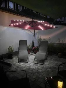 zwei Stühle und ein Regenschirm auf einer Terrasse nachts in der Unterkunft Haus Gaui in Kirrweiler