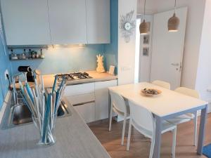 GARDA BLUE HOME on the lake - pool, solarium and garage في توسكولانو ماديرنو: مطبخ مع طاولة وموقد وطاولة وكراسي