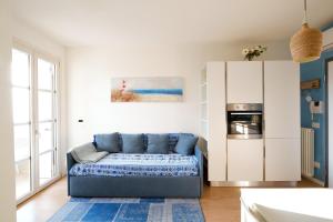 ein Wohnzimmer mit einem blauen Sofa und einer Küche in der Unterkunft GARDA BLUE HOME - Piscina, Solarium e Box in Toscolano-Maderno