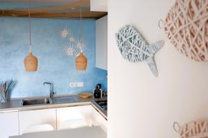 eine Küche mit weißen Schränken und blauen Wänden in der Unterkunft GARDA BLUE HOME on the lake - pool, solarium and garage in Toscolano-Maderno + 37 Fotos