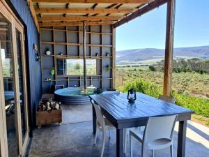 a room with a table and chairs and a hot tub at Slow Track Farm in Baardskeerdersbos
