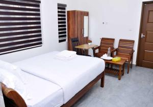 a bedroom with a bed and two chairs and a window at Whiteway Homestay in Kūmudi