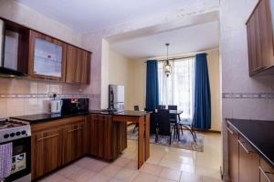 cocina con armarios de madera y comedor con mesa en JCA APARTMENTS, en Nairobi