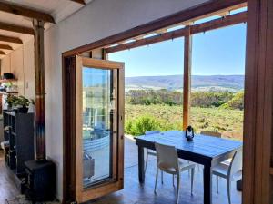 a dining room with a table and chairs and a glass door at Slow Track Farm in Baardskeerdersbos