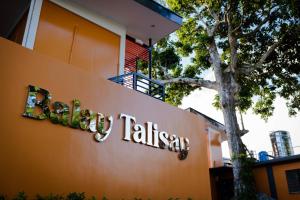 BalogoBalay Talisay的树前的酒店标志
