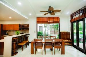 a dining room with a table and chairs and a ceiling fan at 3BR garden pool villas in beach resort in Da Nang