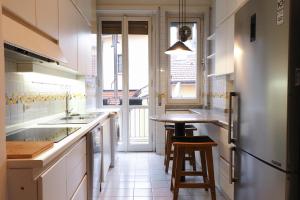 a kitchen with white cabinets and a counter with stools at HomNest I S.Ambrogio Elegant Apt in Milan +15 photos
