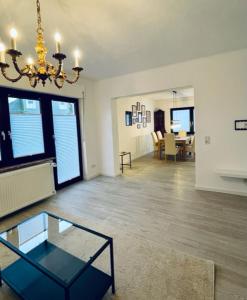 a living room with a chandelier and a glass table at Allegra Appartements in Nohfelden