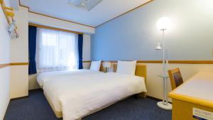 a hotel room with two beds and a window at Toyoko Inn Kagoshima chuo eki Higashi guchi in Kagoshima