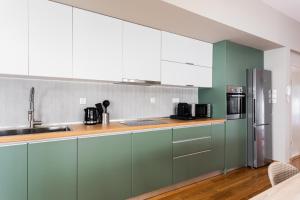uma cozinha com armários verdes e electrodomésticos de aço inoxidável em The Gate by Zoia Living em Atenas