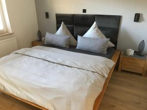 una camera da letto con un grande letto con lenzuola e cuscini bianchi di FeWo Hafenkoje am Timmeler Meer in Großefehn a Timmel